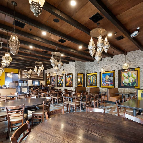 Spacious Azteca D'Oro Mexican restaurant interior with ornate lighting, colorful art, and wooden tables.