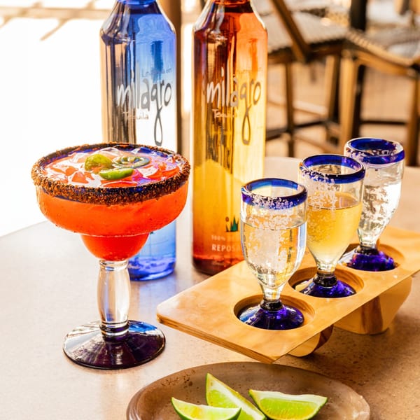 A vibrant red margarita with jalapeños and a tequila flight with lime wedges at Azteca D'Oro.