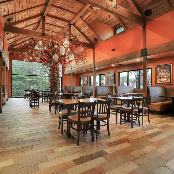 Spacious Azteca D'Oro dining room with high wooden ceilings, orange walls, and a large decorative tree.