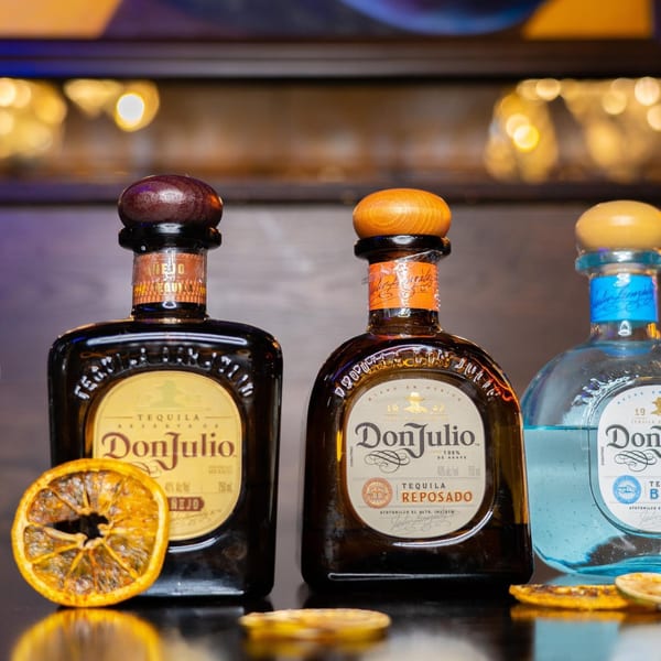 Three bottles of Don Julio tequila, Añejo, Reposado, and Blanco, with dried orange slices.