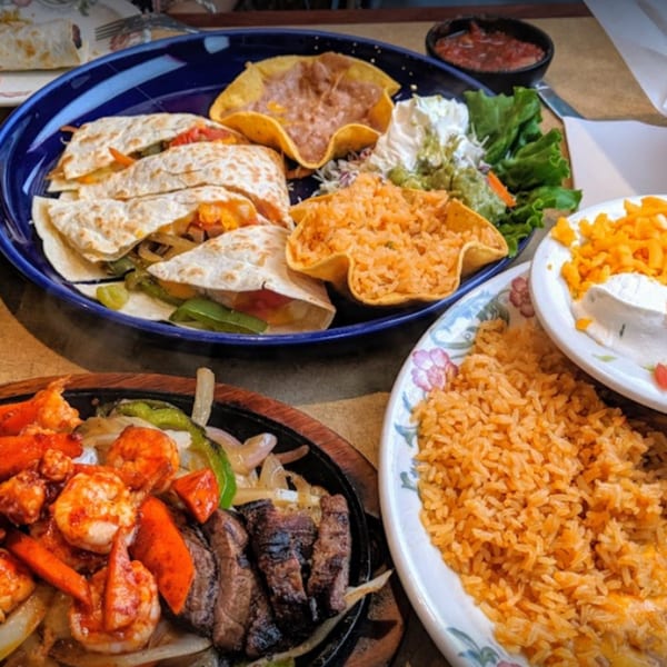 A vibrant Mexican feast with quesadillas, fajitas, rice, beans, and salsa on a table.
