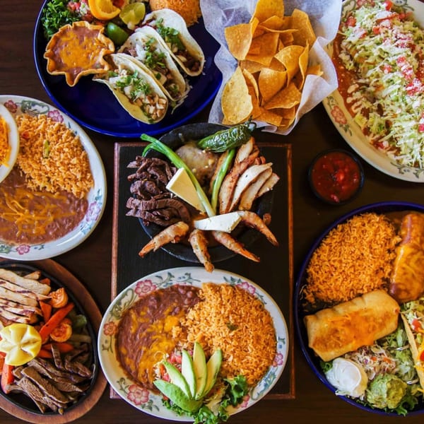 A vibrant spread of Azteca D'Oro Mexican dishes, including tacos, fajitas, rice, beans, and chips.