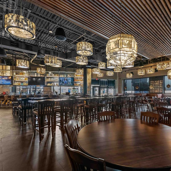 Spacious Azteca D'Oro Mexican restaurant interior with dark wood tables, chairs, and ornate hanging lights.