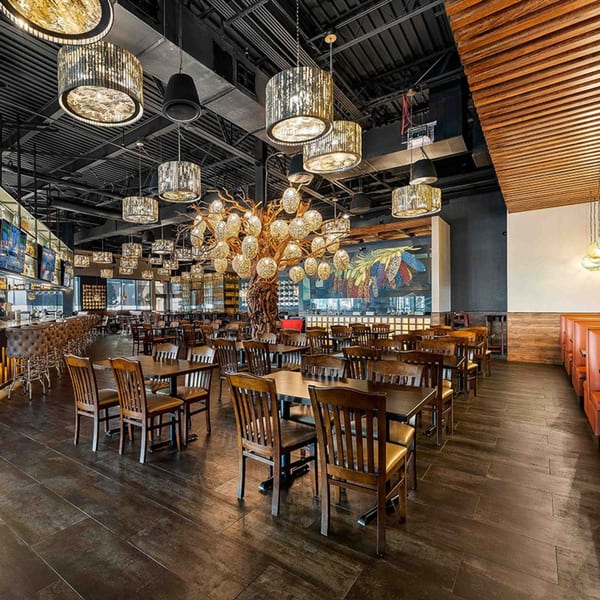 Spacious Azteca D'Oro Mexican restaurant dining room with tables, chairs, bar, and decorative lighting.