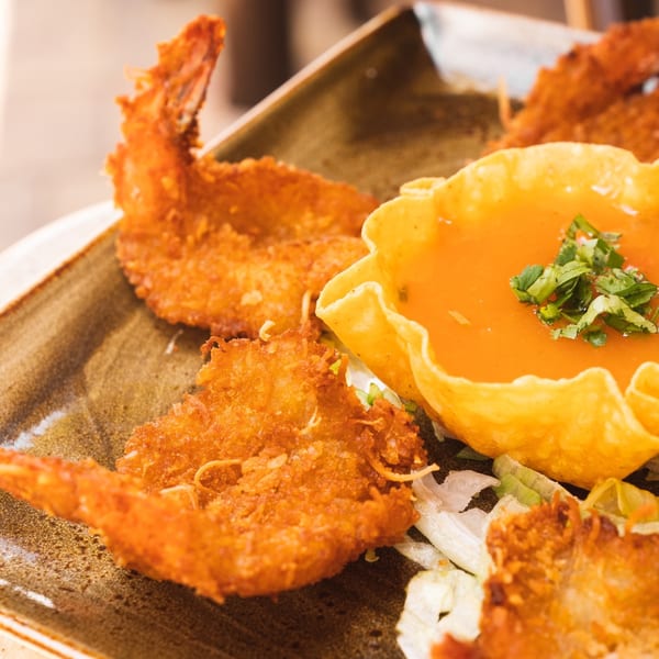 Crispy fried shrimp with a side of orange dipping sauce in a tortilla bowl, garnished with cilantro.