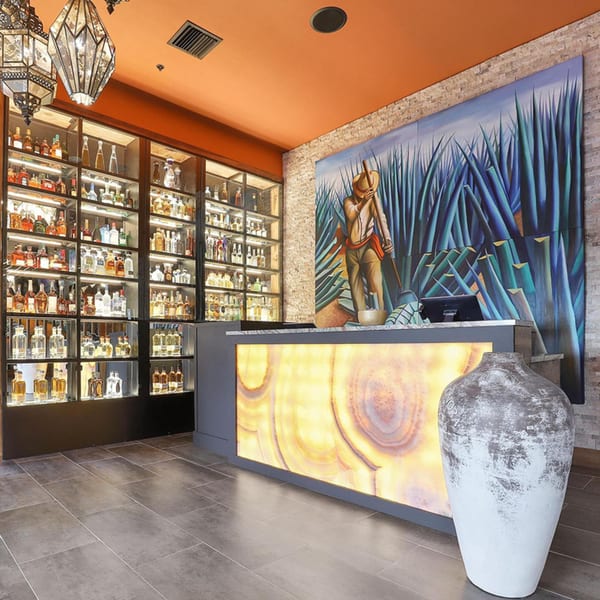 Azteca D'Oro Mexican Restaurant's tequila bar with a large agave field mural and illuminated counter.
