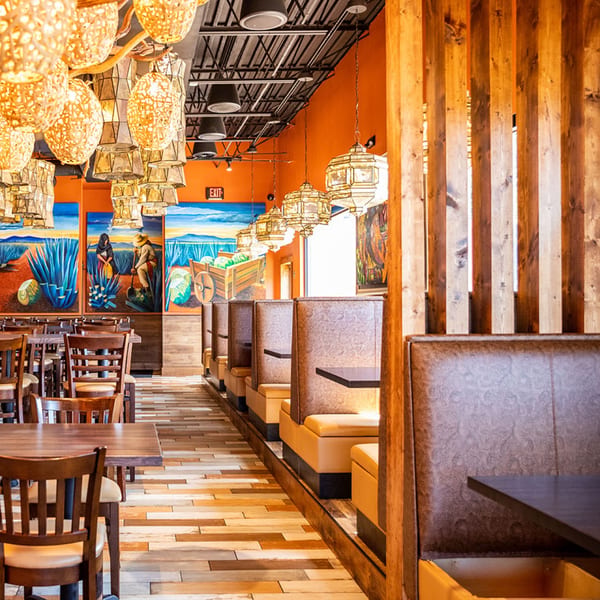 Azteca D'Oro Mexican Restaurant interior with vibrant murals, woven light fixtures, and booth seating.