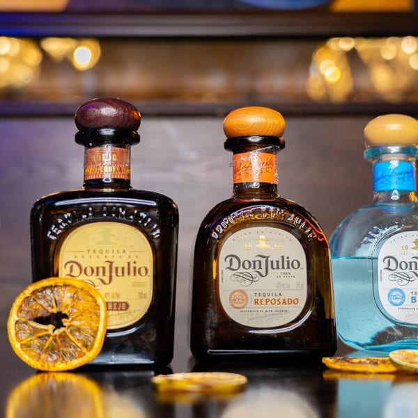 Three bottles of Don Julio tequila, including Añejo, Reposado, and Blanco, with dried orange slices.