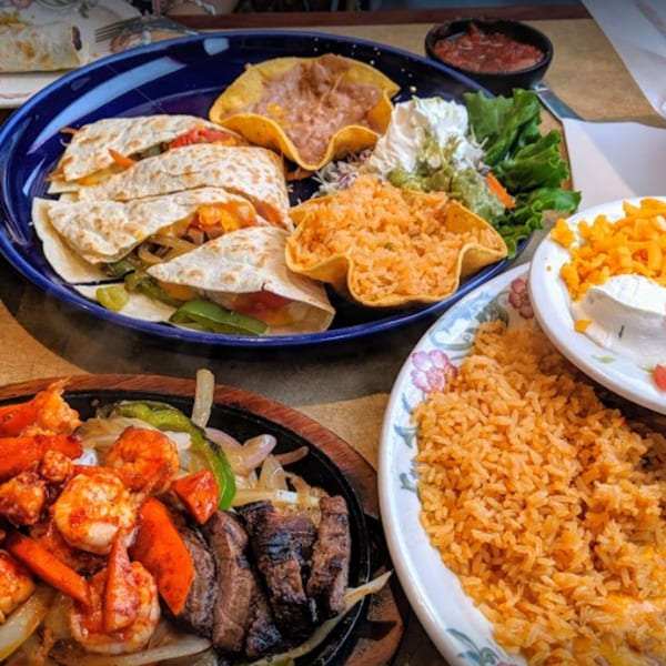 A vibrant Mexican feast featuring fajitas, quesadillas, rice, beans, and salsa on a table.