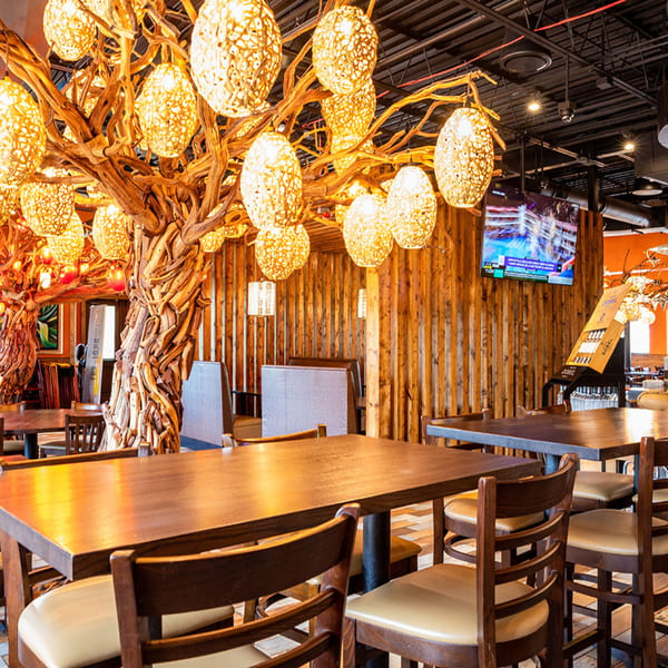 Restaurant interior with wooden tables and chairs, illuminated by decorative tree-like light fixtures.