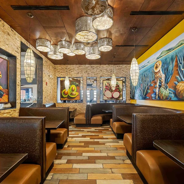 Interior of Azteca D'Oro Mexican Restaurant with brown booths, brick walls, and colorful murals.