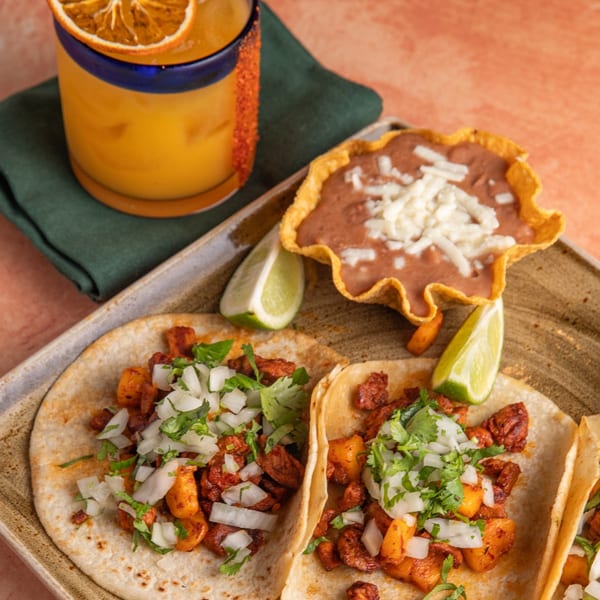 Two Azteca D'Oro Mexican tacos with a side of refried beans and a margarita.