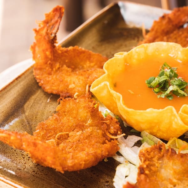 Crispy fried shrimp with a side of orange dipping sauce in a tortilla bowl, garnished with cilantro.