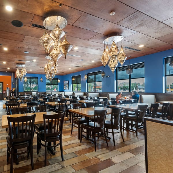 Spacious dining room at Azteca D'Oro Mexican Restaurant with blue walls, wooden tables, and ornate chandeliers.