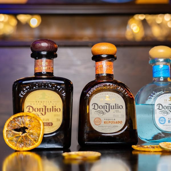 Three bottles of Don Julio tequila, including Añejo, Reposado, and Blanco, with dried orange slices.