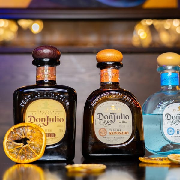 Three bottles of Don Julio tequila, Anejo, Reposado, and Blanco, with dried orange slices.