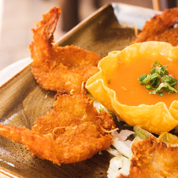 Crispy fried shrimp with a side of orange dipping sauce in a tortilla bowl, garnished with cilantro.