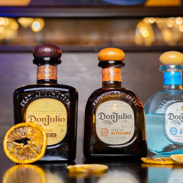 Three bottles of Don Julio tequila, including Añejo, Reposado, and Blanco, with dried orange slices.